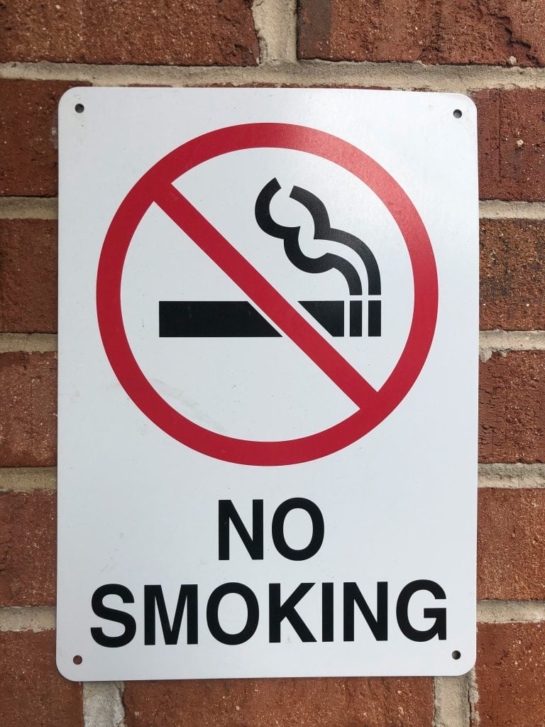 No smoking sign displayed on a brick wall.